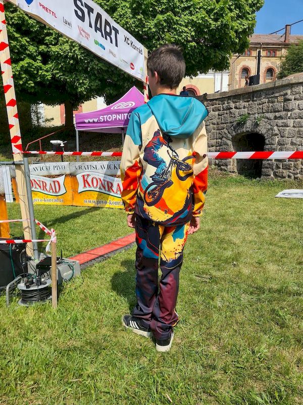 Junge auf einer Wiese, er trägt die Wamu Softshell Kombination Mountain Bike mit dunklen Hosen
