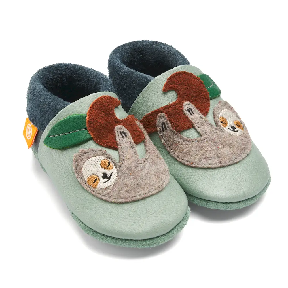 Lederfinken in hellem Mint mit einem grauen Faultier, das an einem Ast hängt und schläft