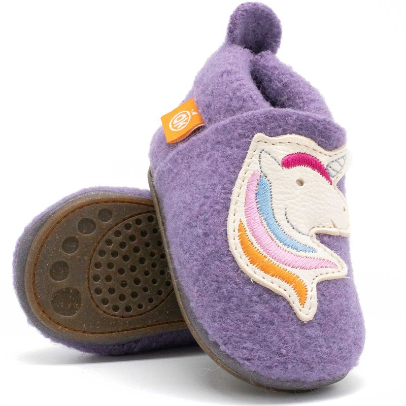 Detailansicht eines lila Kinderhausschuhs aus Wolle mit aufgenähtem Einhornkopf und bunten Stickereien, gummierte Sohle sichtbar