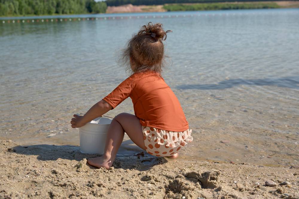 Mädchen mit Lässig Badehose "Dots Powder Pink" und UV-Shirt Toucan