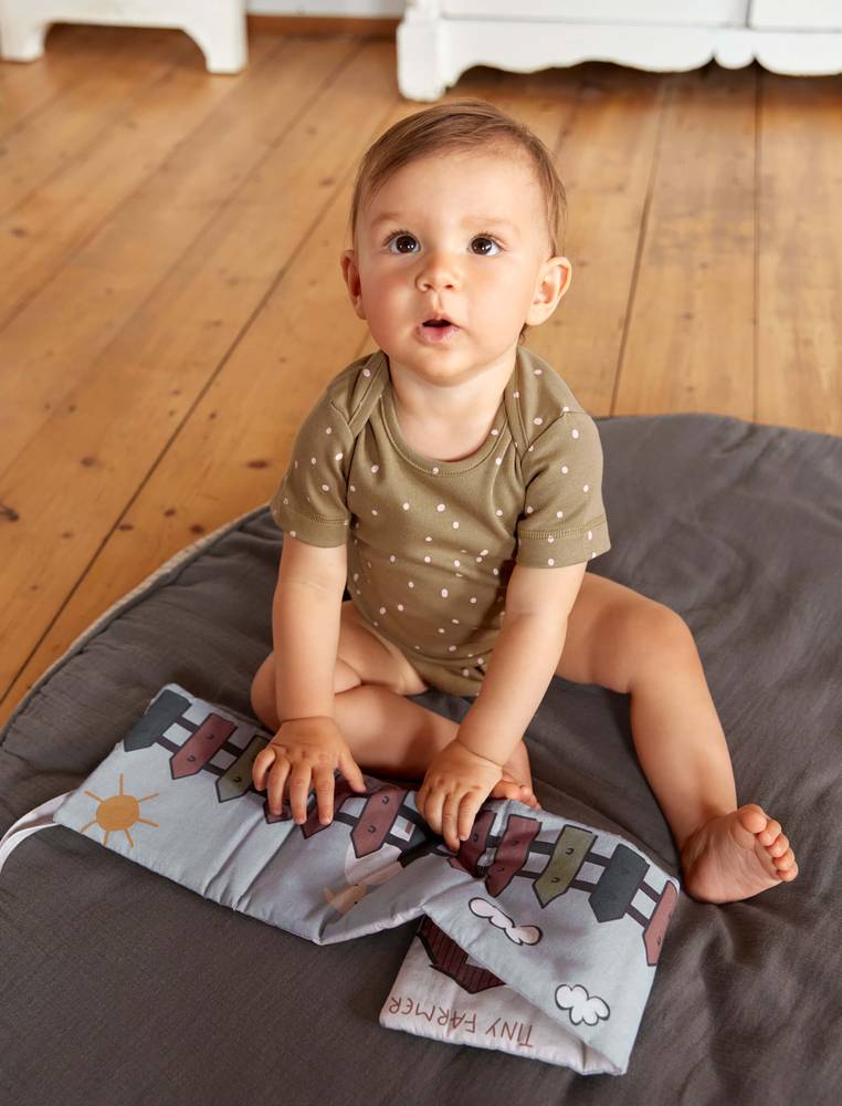 Baby mit dem "Tiny Farmer" Fühlbuch von LÄSSIG 