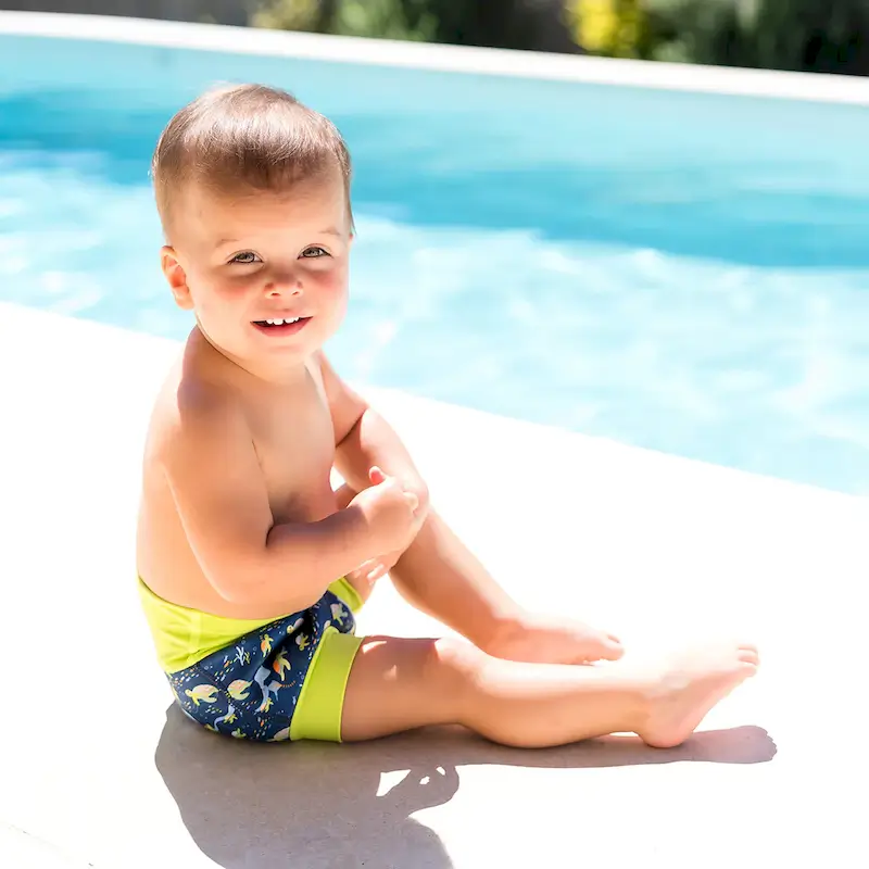 Baby sitzt entspannt am Poolrand und trägt eine sicher sitzende Schwimmwindel für unbeschwerten Badespass